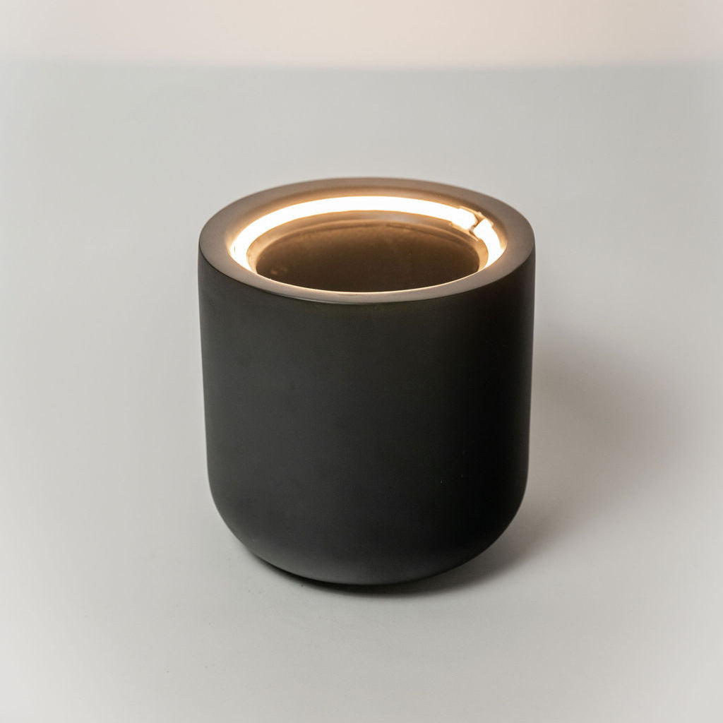 Black ceramic pot with gold interior on a light gray background